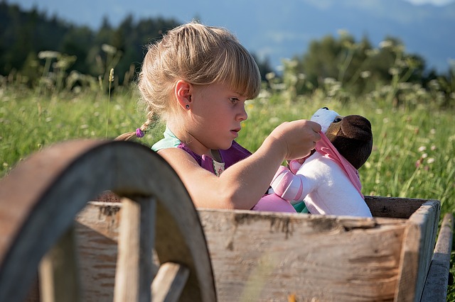dívka sedící venku v přírodě a hrající si s panenkou